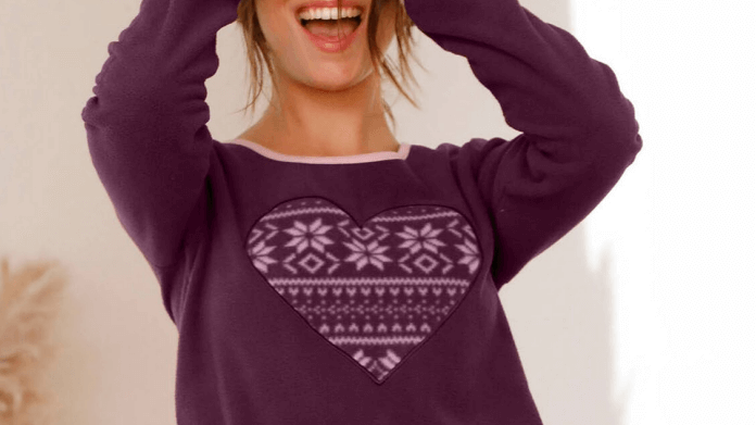 A woman is wearing a Blancheporte burgundy long sleeve top. She is smiling and looking to the side. She put a book on her head. She's happy.